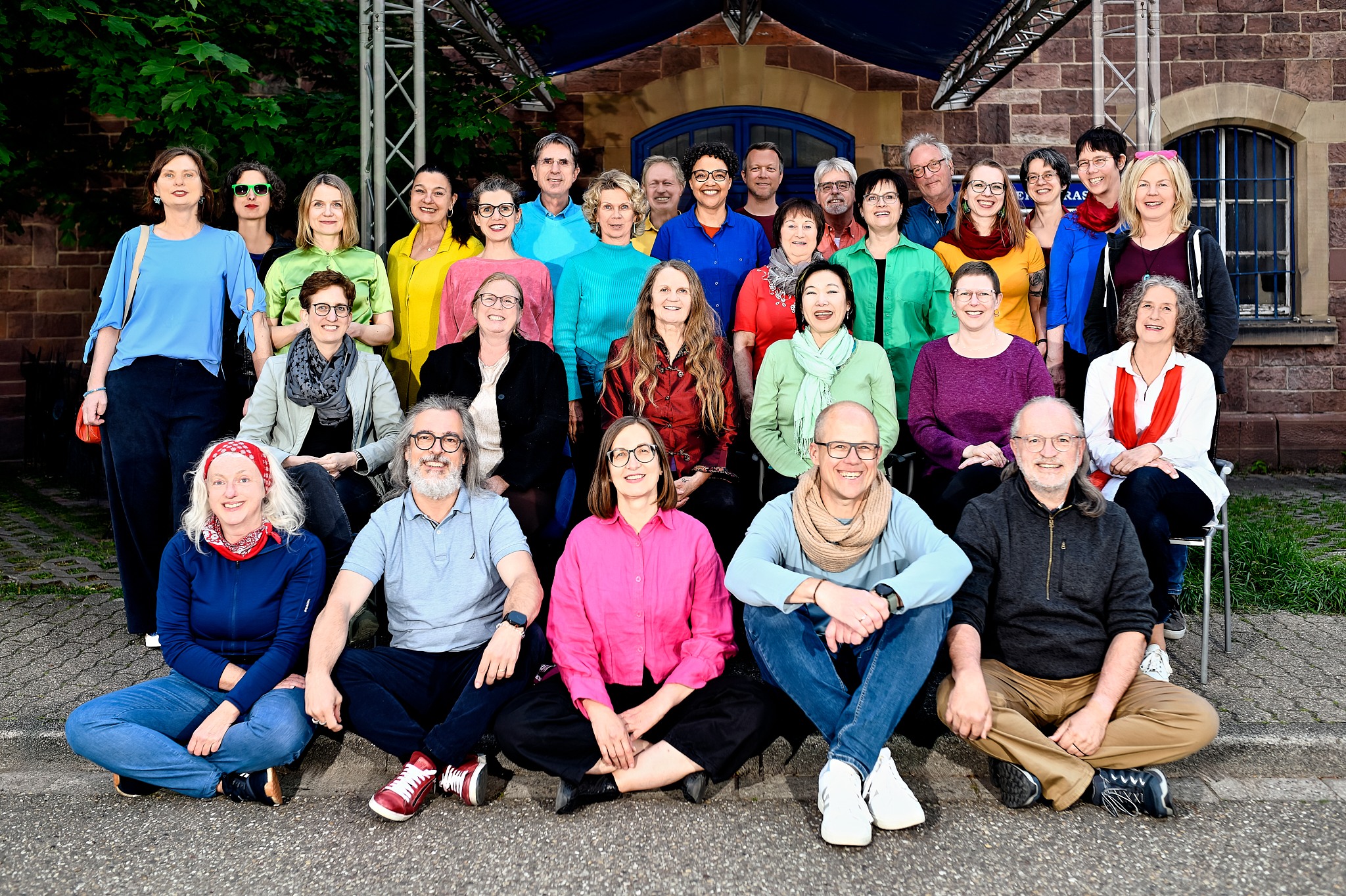 Ein Gruppenfoto mit 29 Chromitgliedern in bunten Hemden vor dem Eingang der Musikschule.